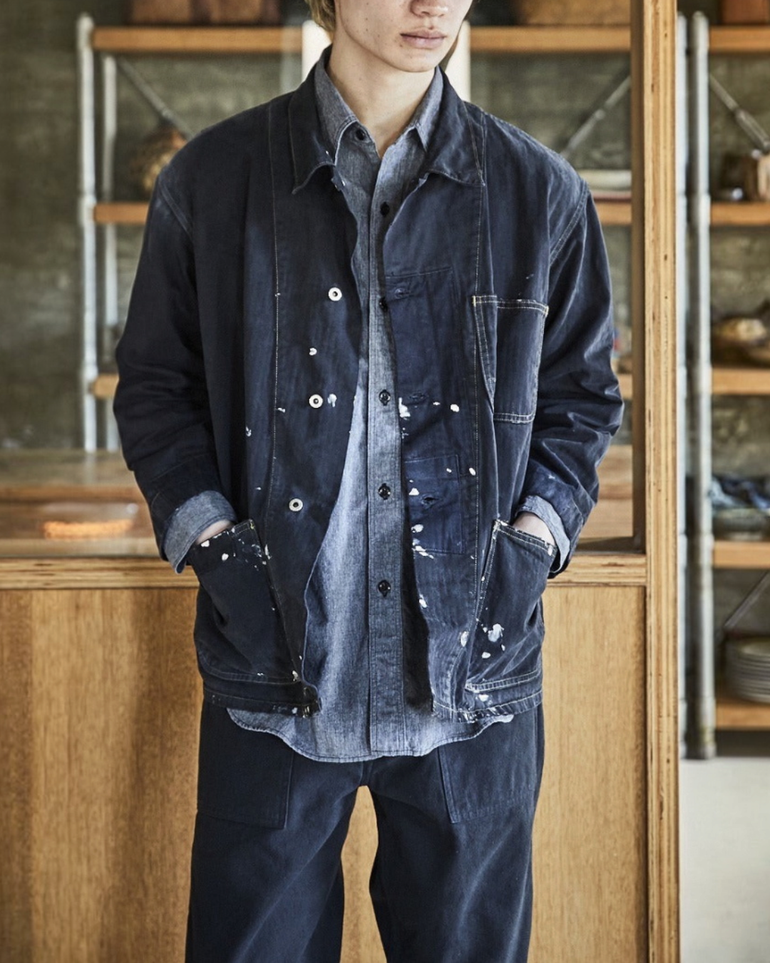 Homme portant une veste de travail Merci Paris OrSlow noire en coton chevron avec effets de peinture blanche