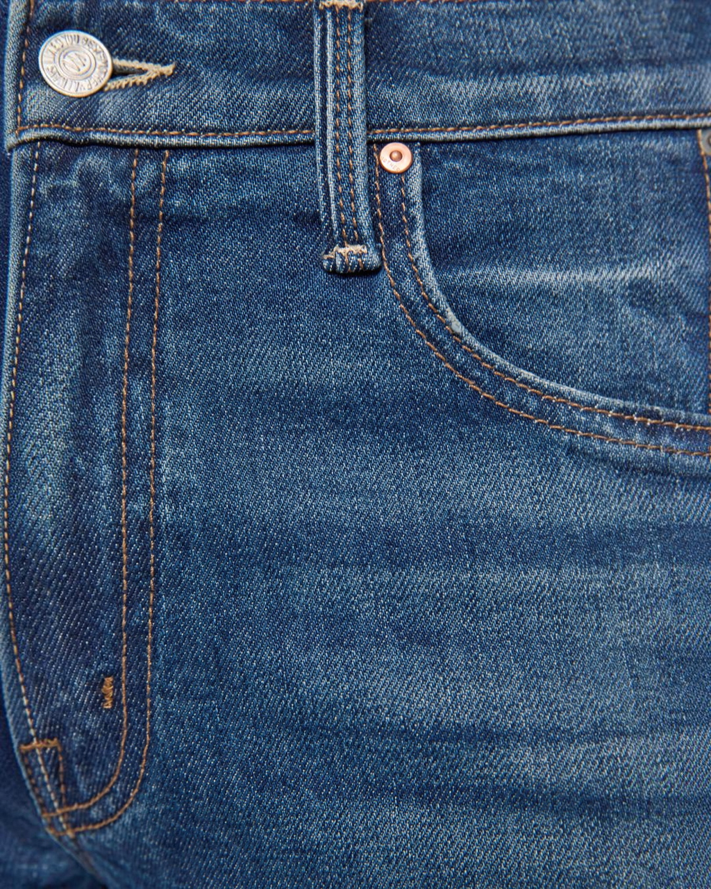 Gros plan sur la taille et la poche d'un jean bleu MOTHER Merci Paris en denim semi-rigide avec surpiqûres contrastées