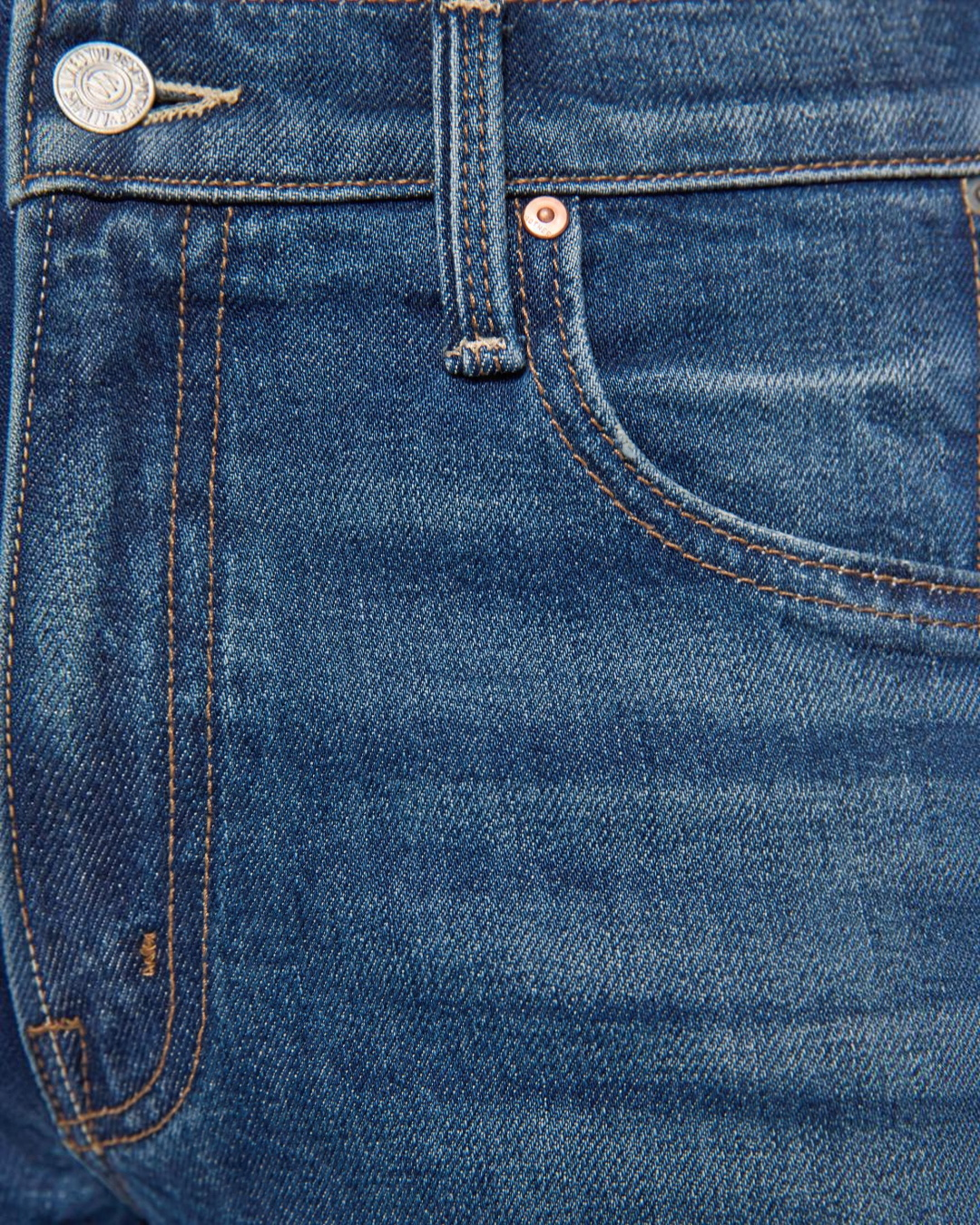 Gros plan sur la taille et la poche d'un jean bleu MOTHER Merci Paris en denim semi-rigide avec surpiqûres contrastées