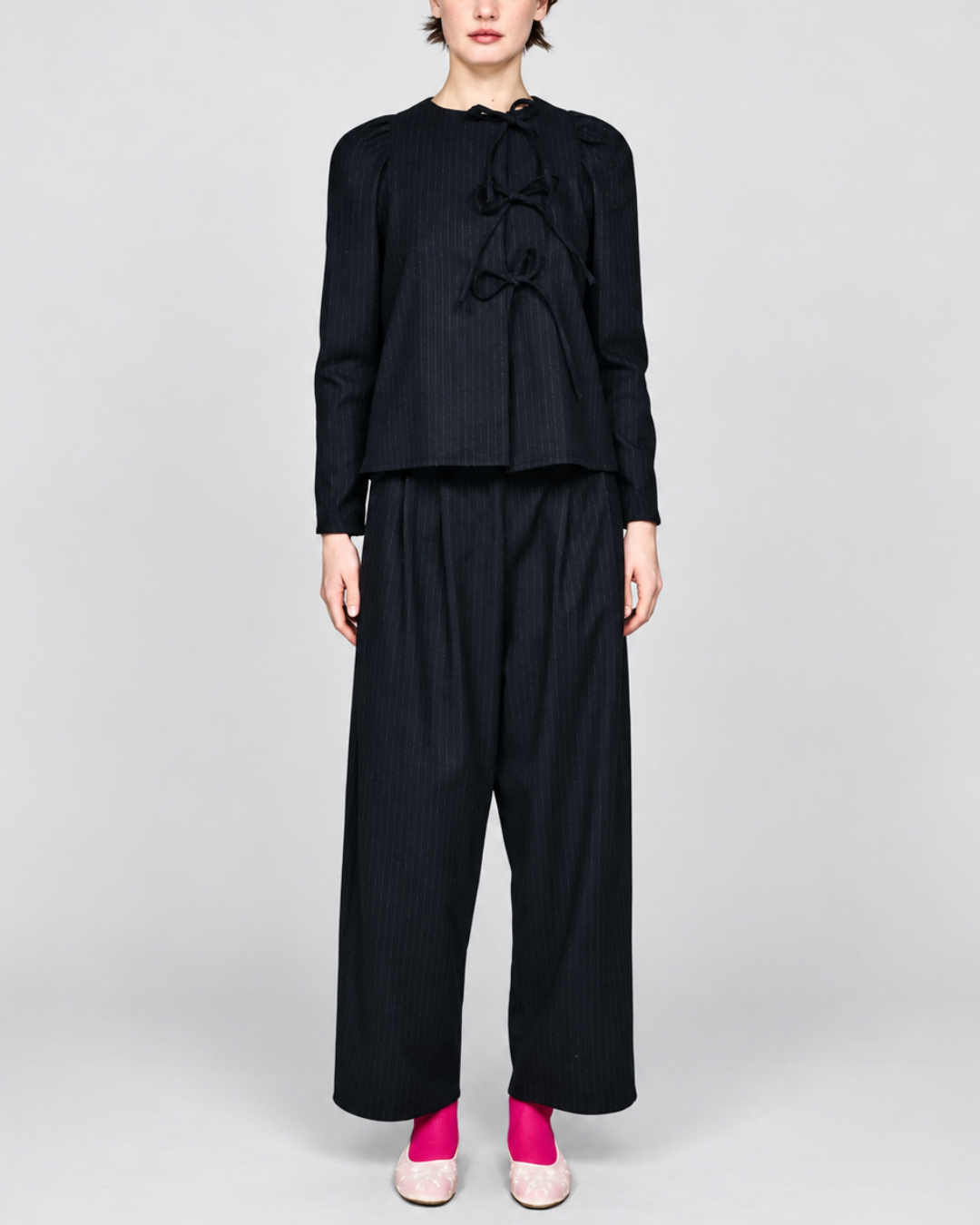 Modèle portant la chemise noire à rayures tennis ELEPH avec fermeture à nœuds et épaules froncées chez Merci Paris