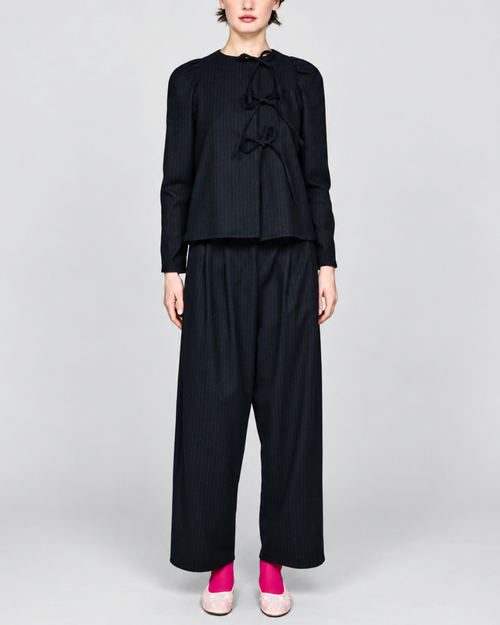 Modèle portant la chemise noire à rayures tennis ELEPH avec fermeture à nœuds et épaules froncées chez Merci Paris