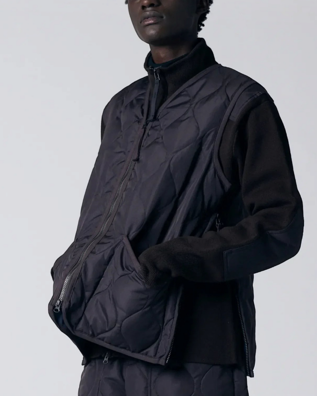 Gilet matelassé Merci Paris Taion chocolat à col en V, fermeture zippée et tissu ripstop porté par un mannequin