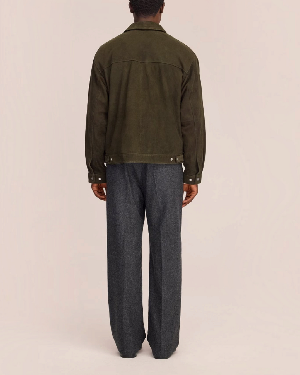 Vue arrière d'un homme portant la veste Petrus en daim vert de Merci Paris avec un pantalon gris