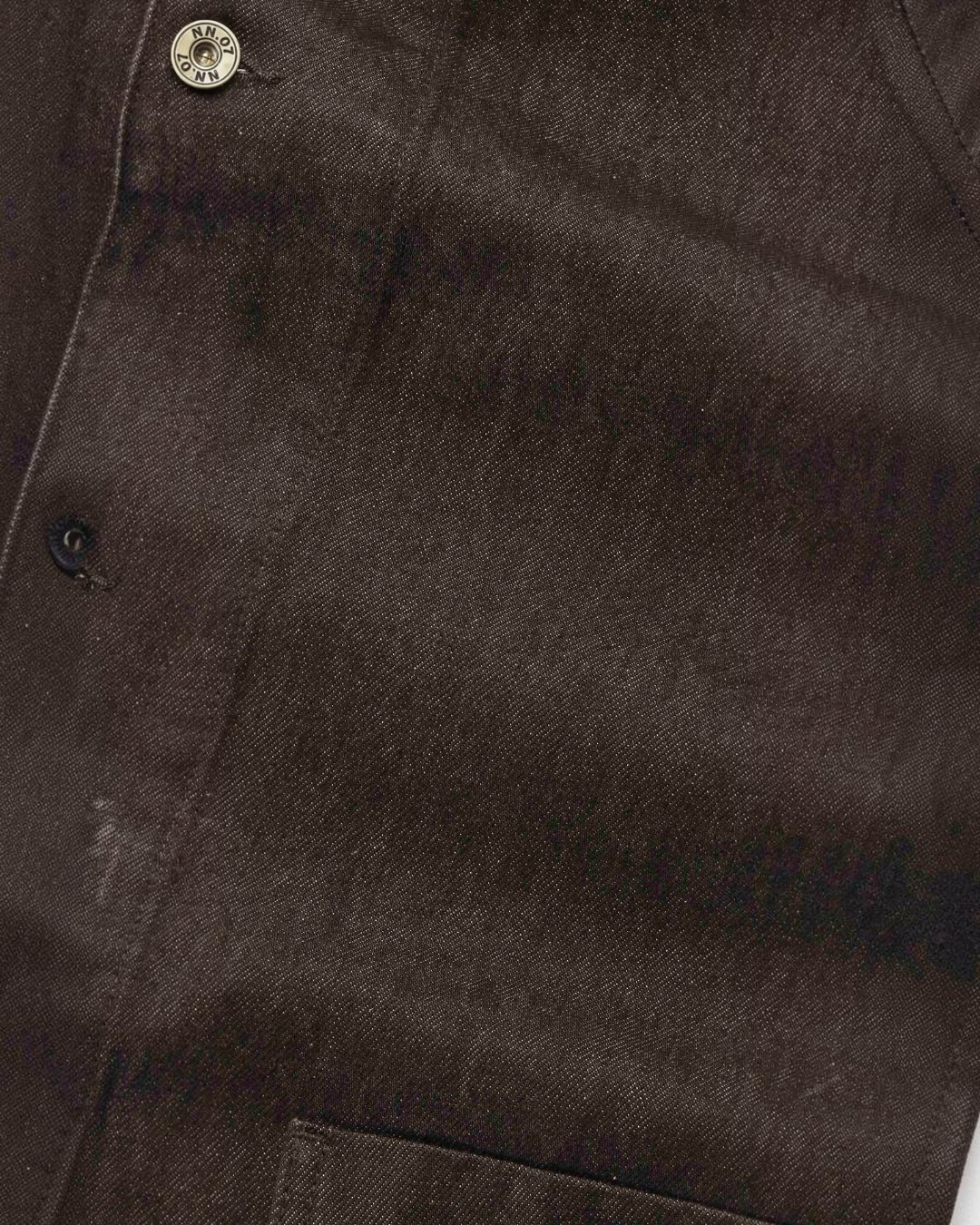 Gros plan sur la veste Aiko marron en denim de coton épais de Merci Paris, avec bouton en laiton vieilli siglé NN.07