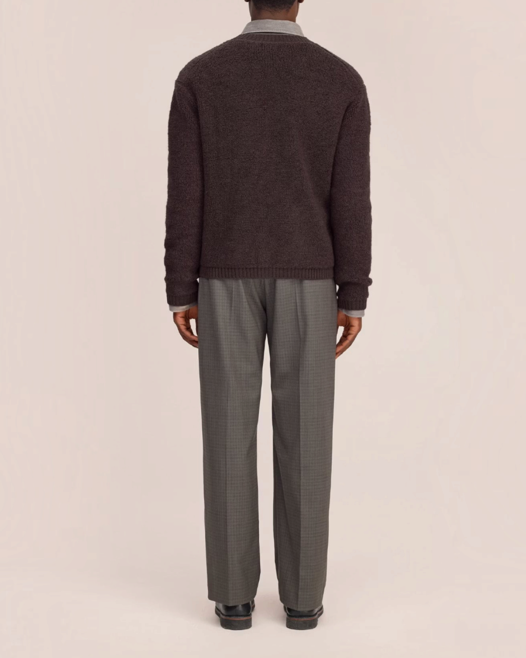 Vue arrière d'un homme portant un cardigan en laine marron NN.07 de Merci Paris sur une chemise et un pantalon gris