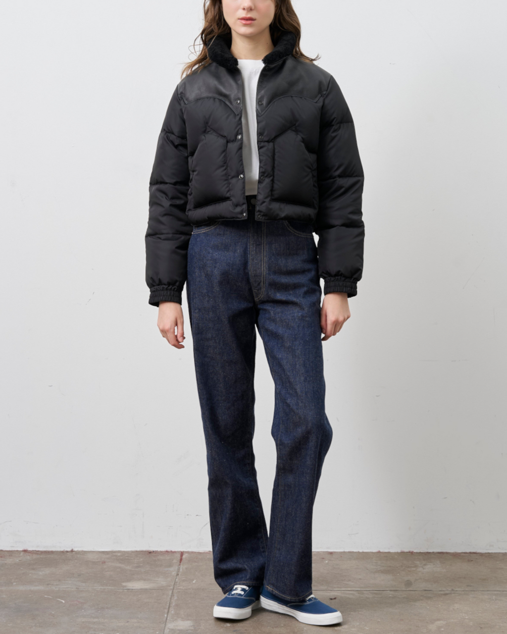 Modèle portant la veste courte noire Annelle de Merci Paris avec col en peau lainée et empiècement en cuir