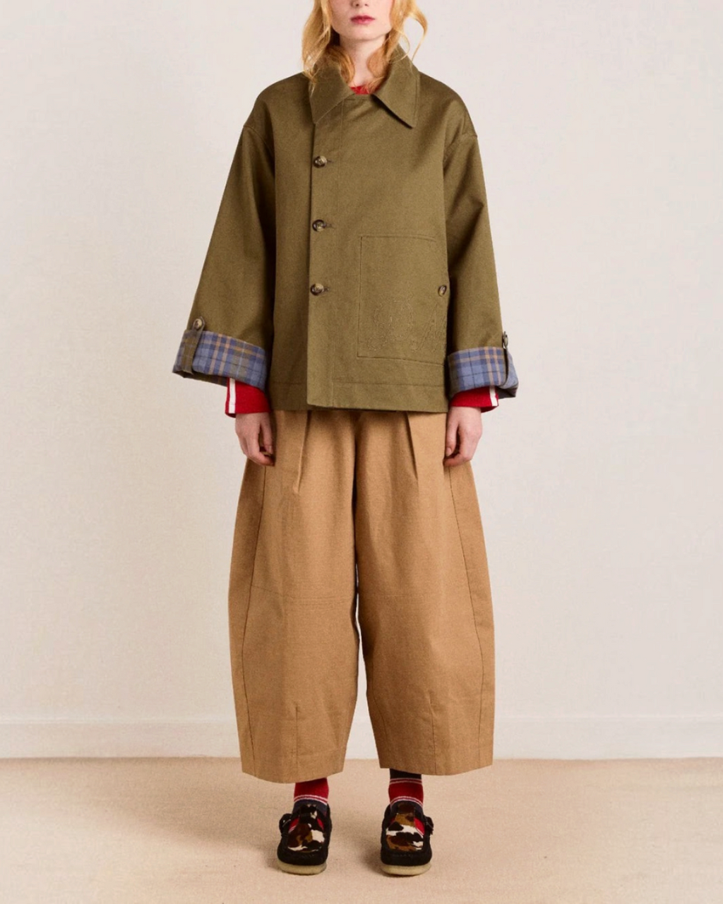 Modèle portant le trench court réversible Jerry couleur olive de Merci Paris en coton biologique avec revers à carreaux