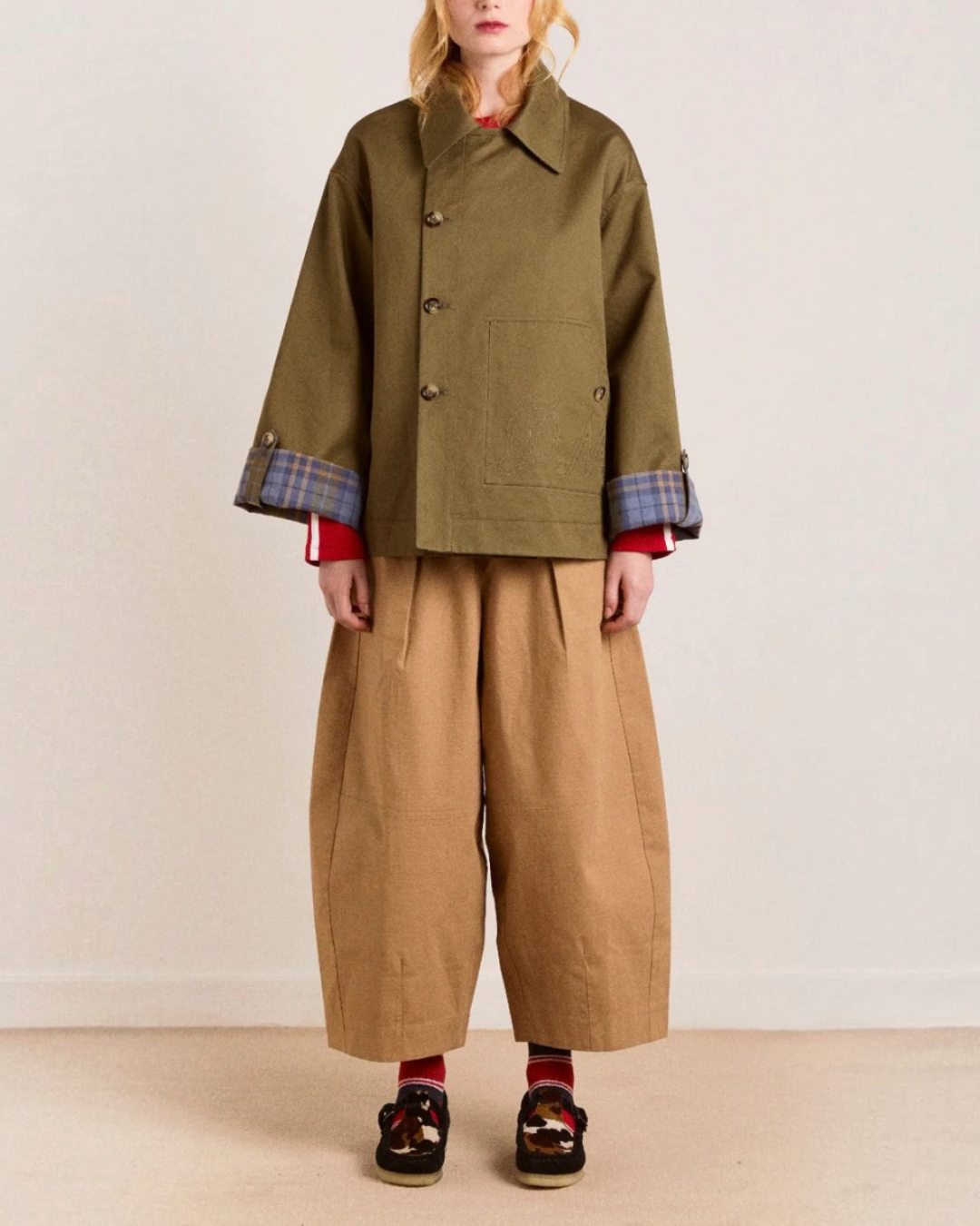 Modèle portant le trench court réversible Jerry couleur olive de Merci Paris en coton biologique avec revers à carreaux