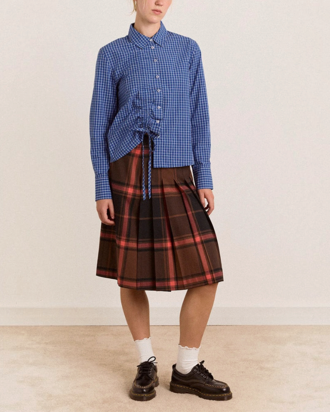 Modèle portant la chemise Damson Madder à carreaux bleus en coton biologique avec détails froncés sur le devant