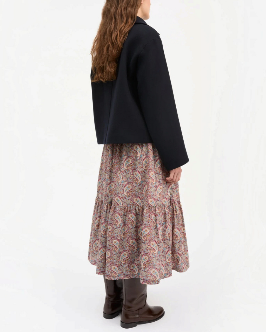 Short navy jacket Skall Studio in recycled wool worn by a woman with a long patterned skirt