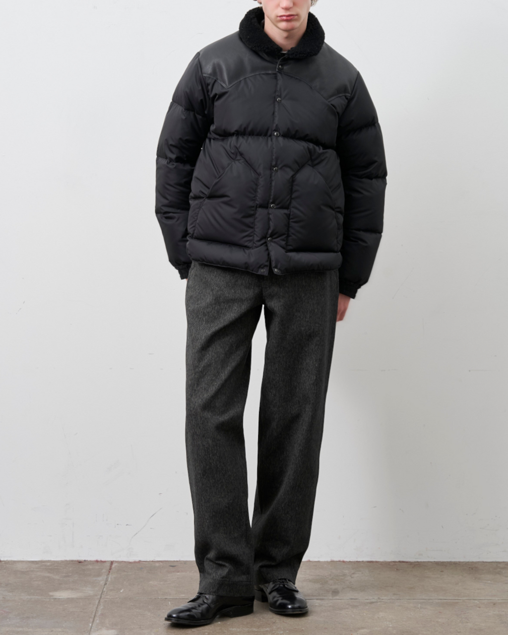 Homme portant une doudoune noire Merci Paris Rocky Mountain avec empiècement en cuir et col en peau lainée