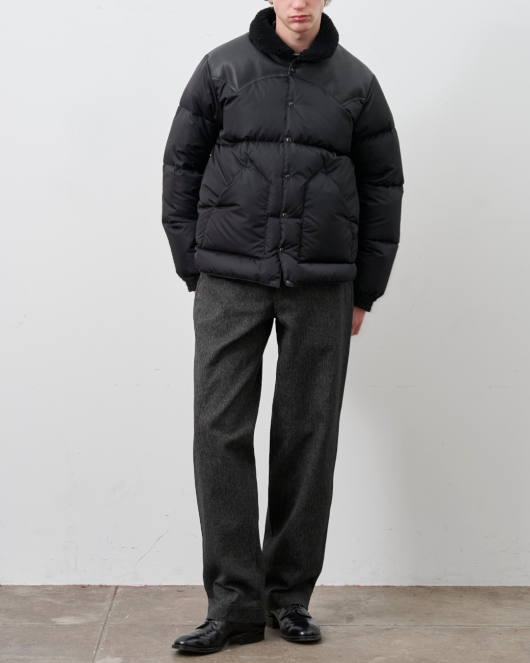 Homme portant une doudoune noire Merci Paris Rocky Mountain avec empiècement en cuir et col en peau lainée