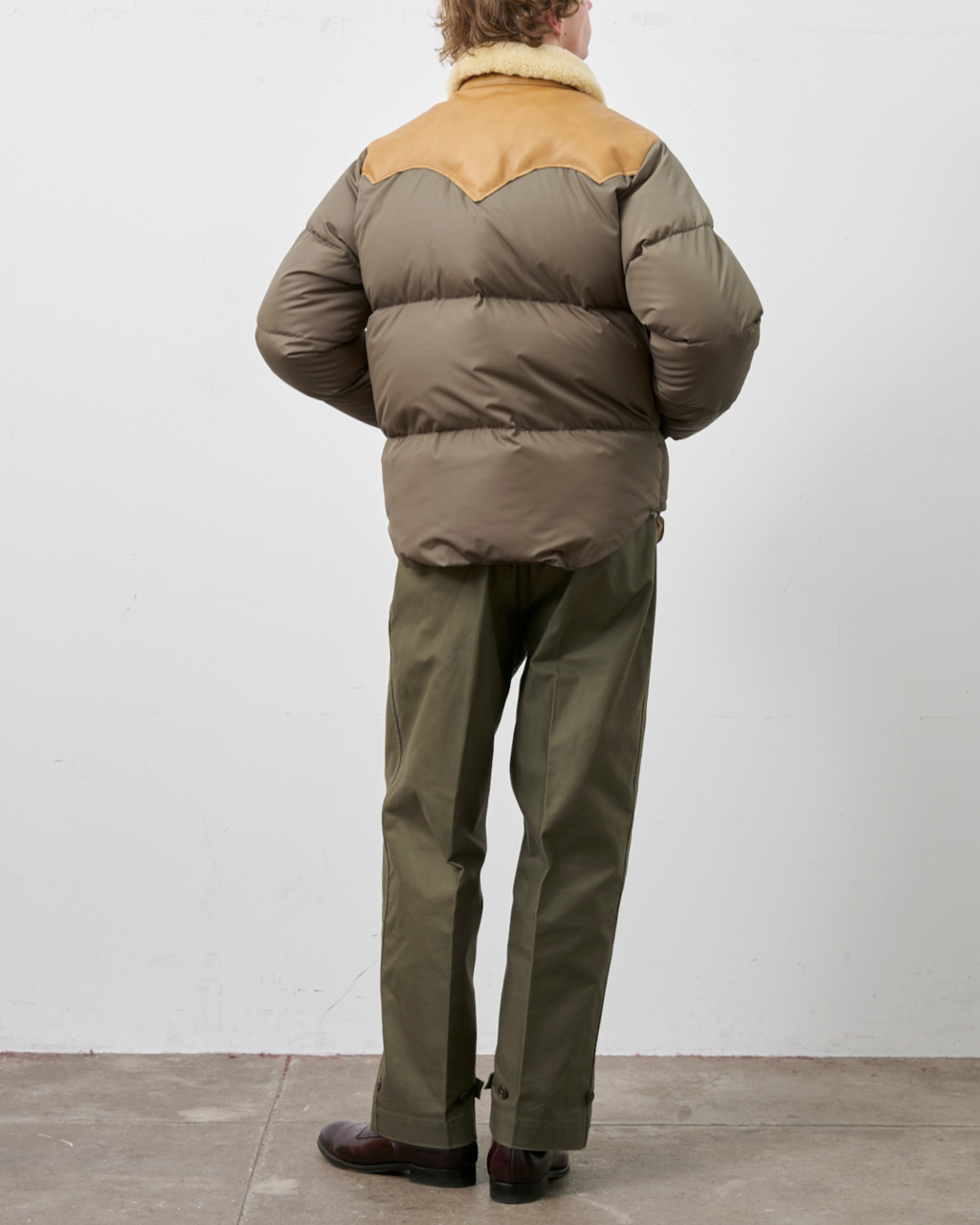 Homme portant la veste Christy Merci Paris en nylon olive avec empiècement en cuir et col en peau lainée, vue dos