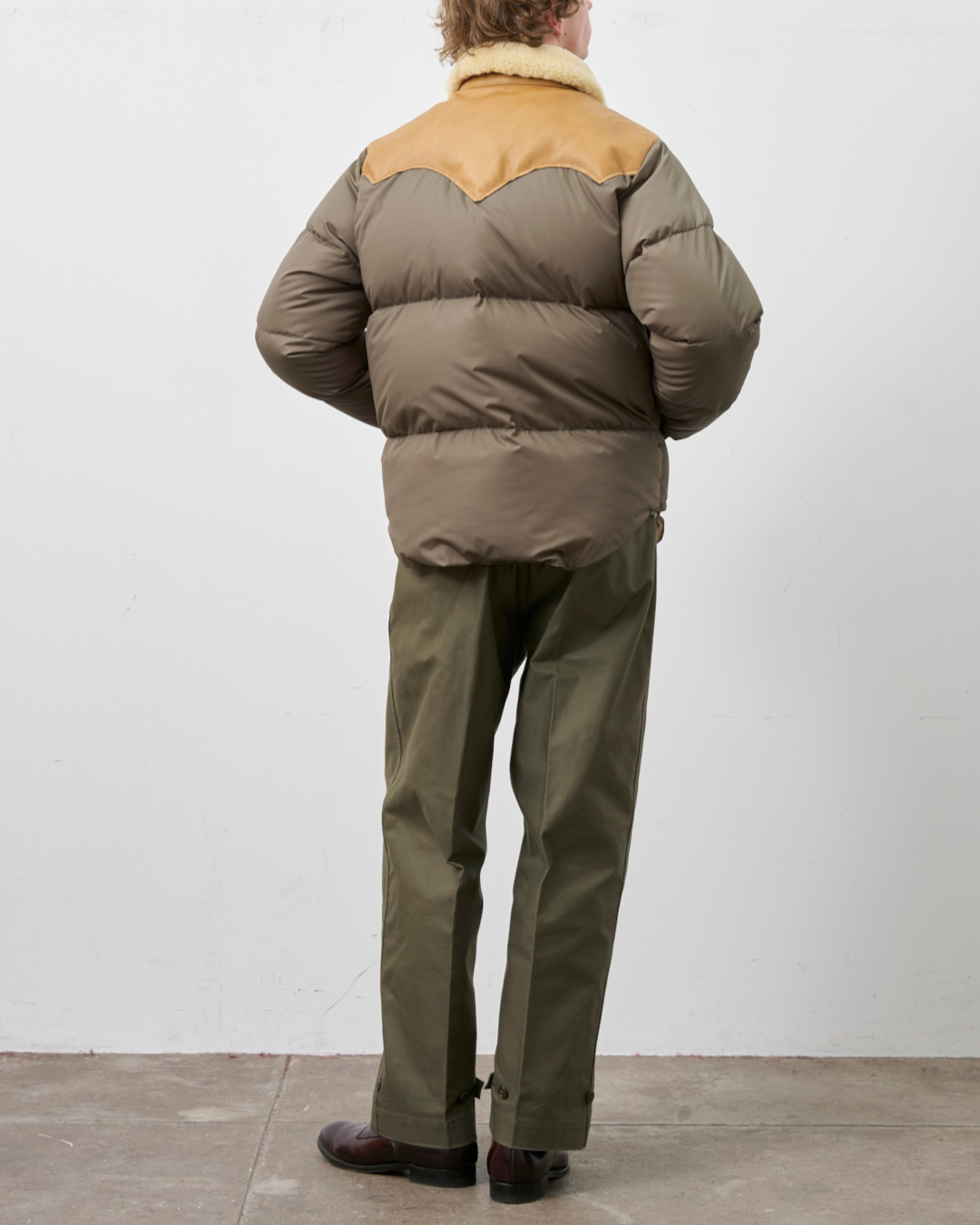 Homme portant la veste Christy Merci Paris en nylon olive avec empiècement en cuir et col en peau lainée, vue dos