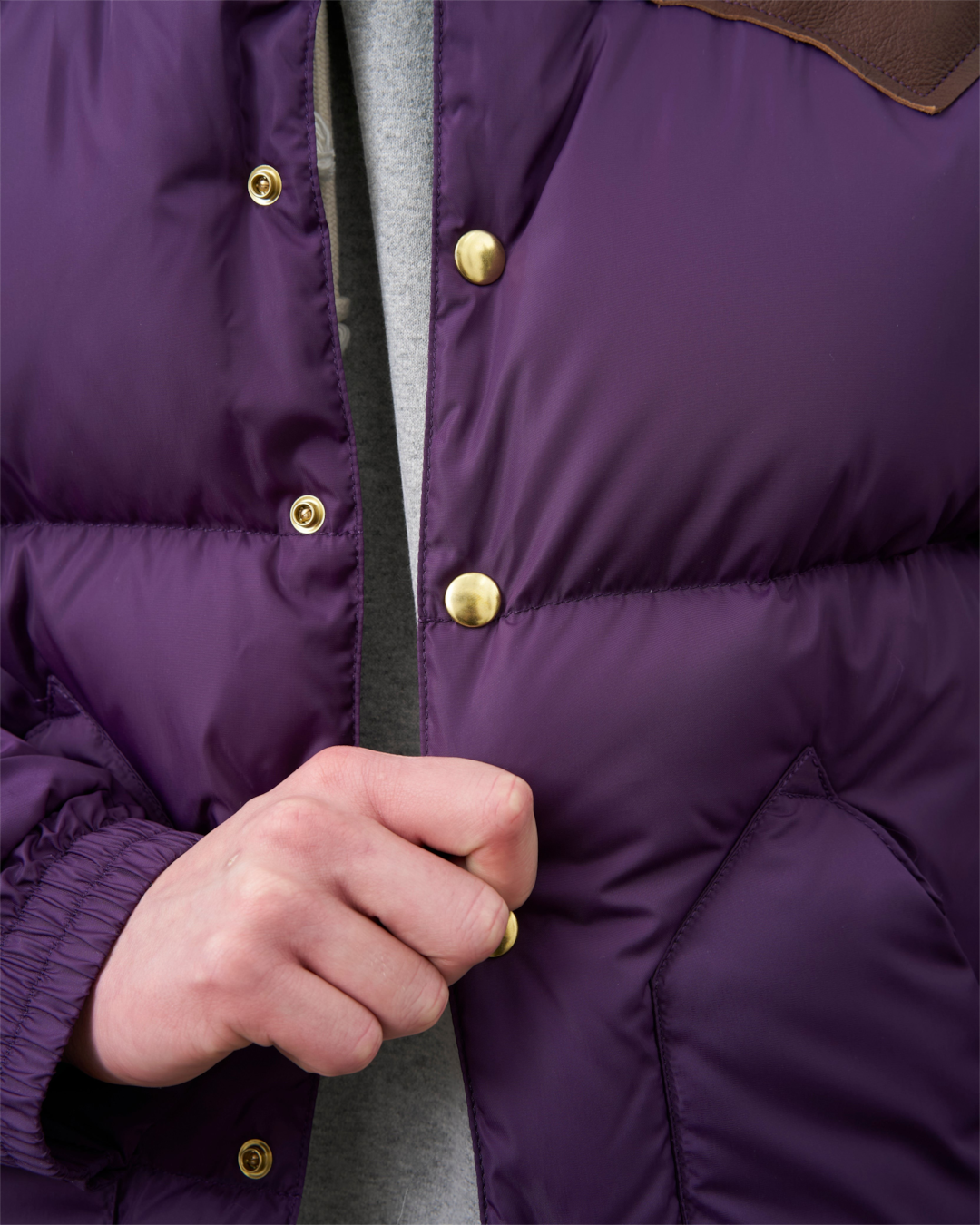 Détail de la veste en duvet Merci Paris Rocky Mountain violette avec empiècement en cuir marron et boutons dorés