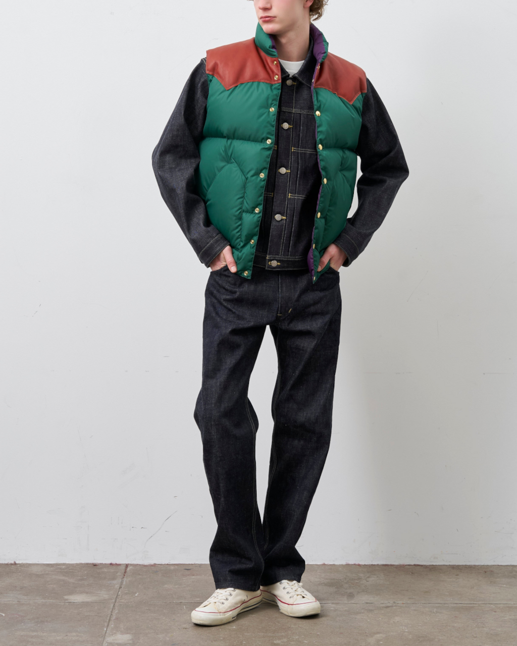 Homme portant un gilet en duvet Merci Paris Rocky Mountain vert et marron avec empiècement en cuir sur une veste denim