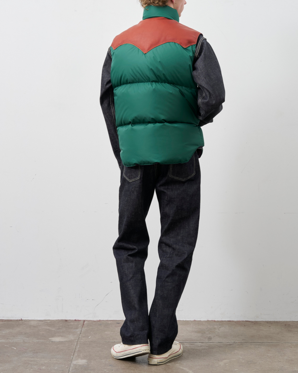 Homme portant un gilet en duvet Merci Paris Rocky Mountain vert avec empiècement en cuir marron, vue de dos