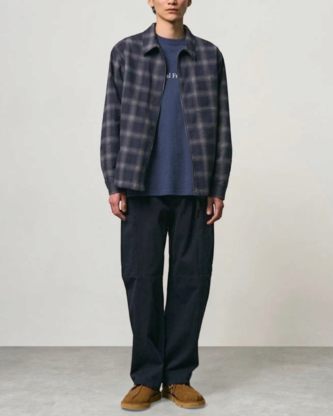 Homme portant le pantalon Voyageur bleu marine Gramicci de Merci Paris avec une chemise à carreaux et chaussures