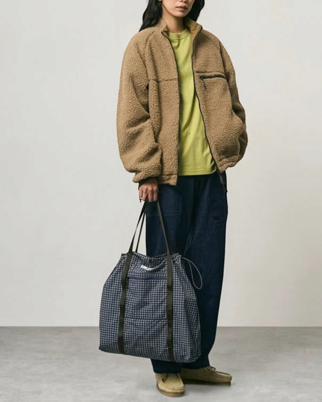 Modèle portant un sac cabas Merci Paris Gramicci bleu à carreaux en coton et nylon avec anses et cordon ajustable