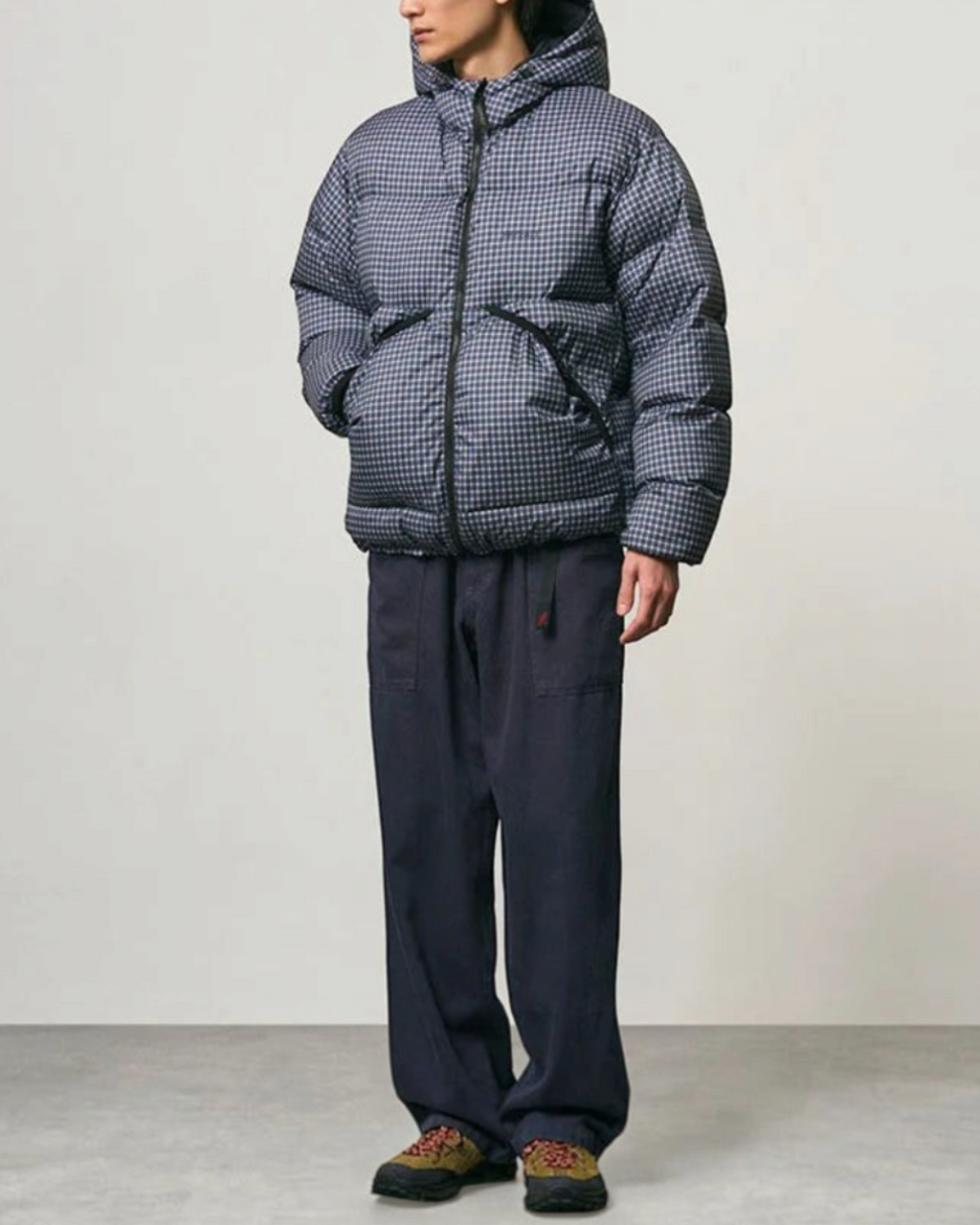 Homme portant une doudoune à capuche Merci Paris Gramicci Coldfront à carreaux bleus et noirs, style alpinisme