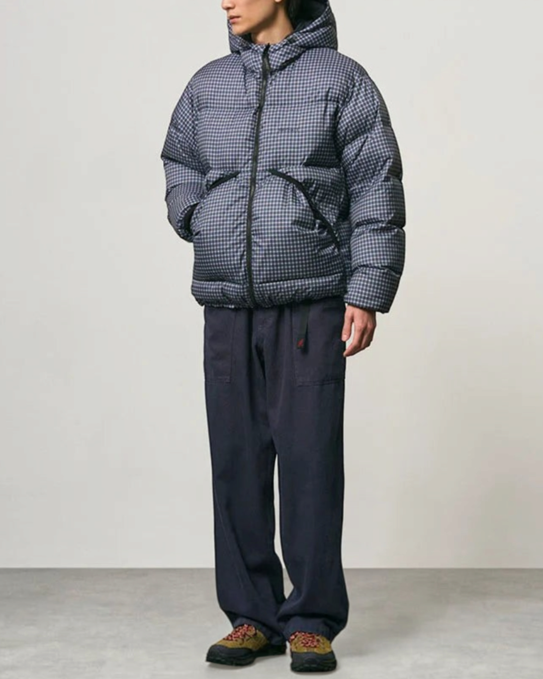 Homme portant une doudoune à capuche Merci Paris Gramicci Coldfront à carreaux bleus et noirs, style alpinisme