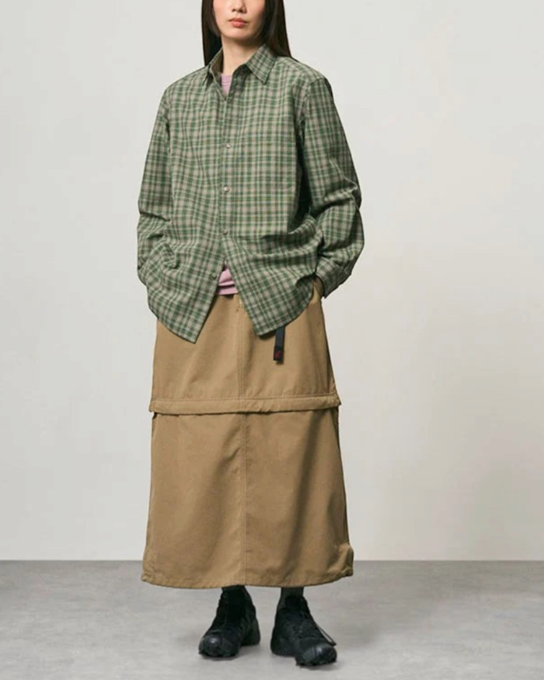 Mannequin portant une chemise Gramicci épaisse à carreaux verts et une jupe longue beige dans un style décontracté