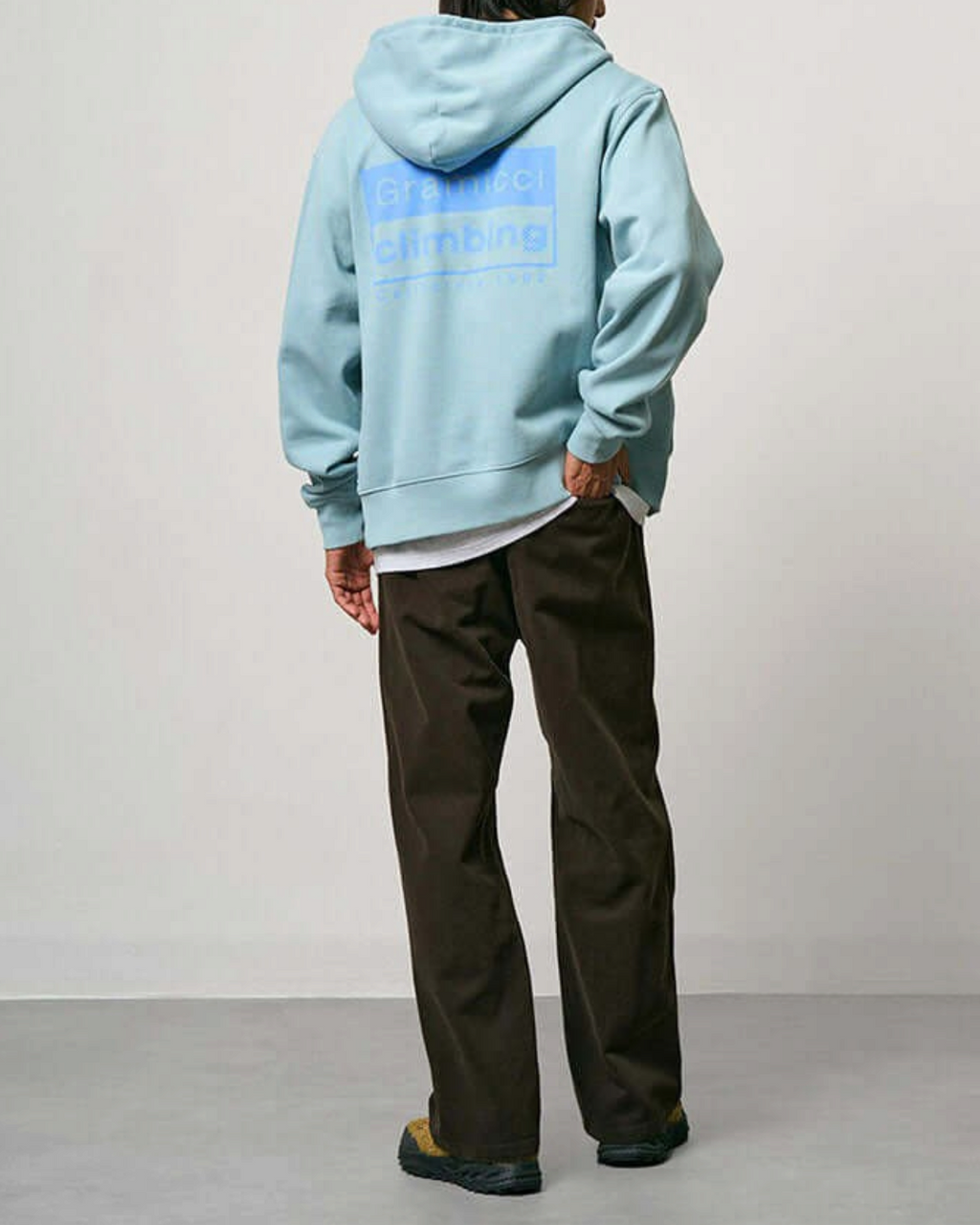 Homme portant un pantalon Gramicci marron en coton épais et un sweat à capuche bleu clair Merci Paris