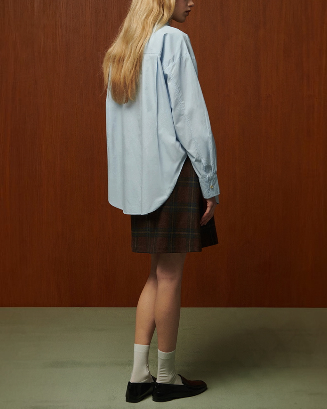 Modèle portant la chemise Ava en popeline de coton bleu clair de Merci Paris, vue de dos avec fentes latérales.