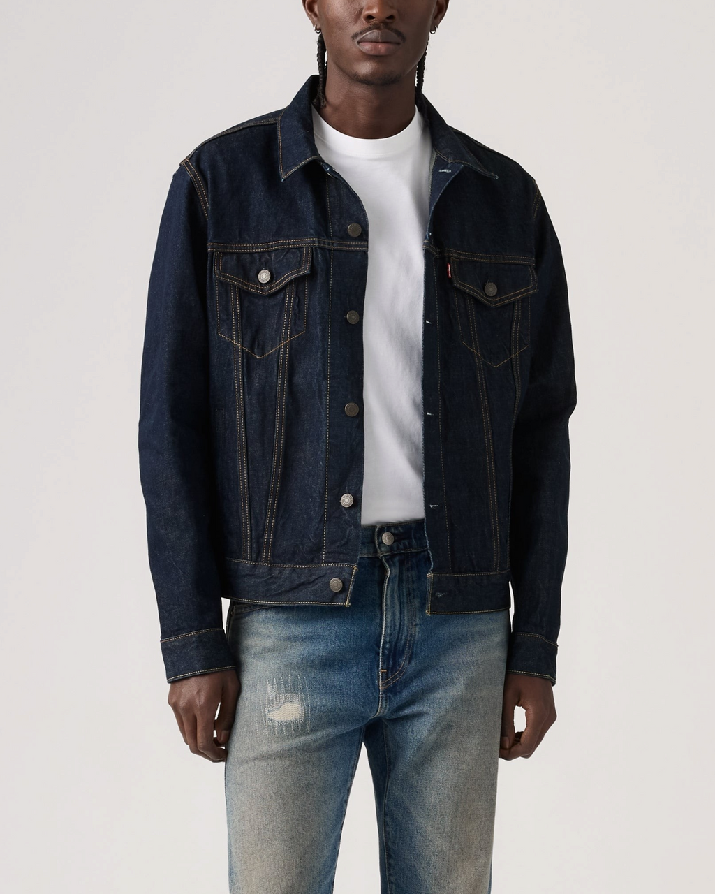 Homme portant une veste Trucker en denim bleu brut Merci Paris avec des surpiqûres contrastées et boutons métalliques