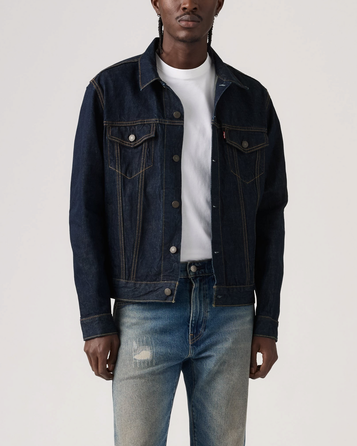 Homme portant une veste Trucker en denim bleu brut Merci Paris avec des surpiqûres contrastées et boutons métalliques