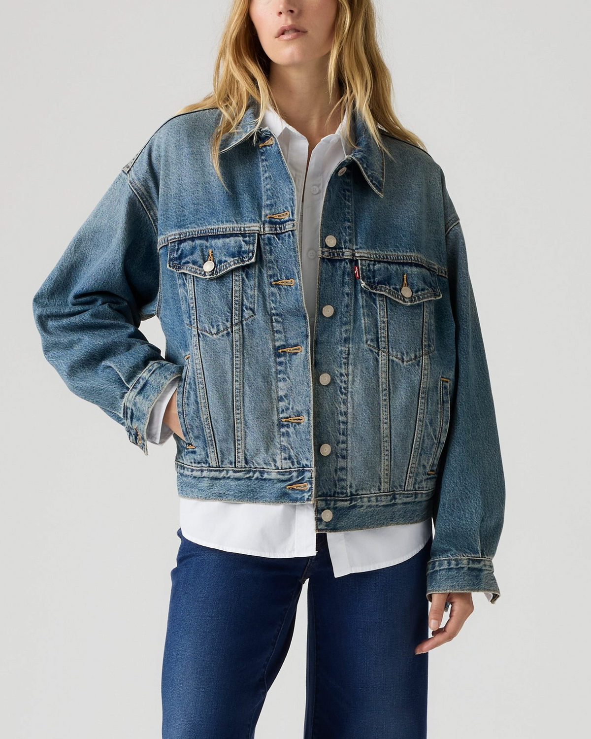 Modèle portant la veste en jean Merci Paris Levi's 90 Trucker bleu délavé avec coupe décontractée et poches à rabat.