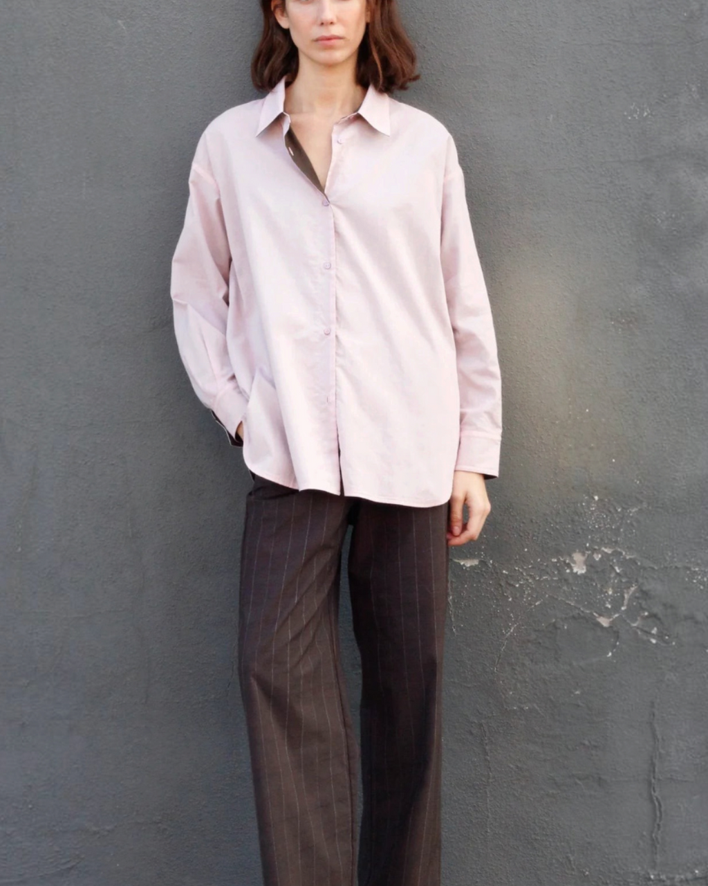Mannequin portant la chemise réversible Merci Paris en coton biologique rose oversize avec col et revers marron