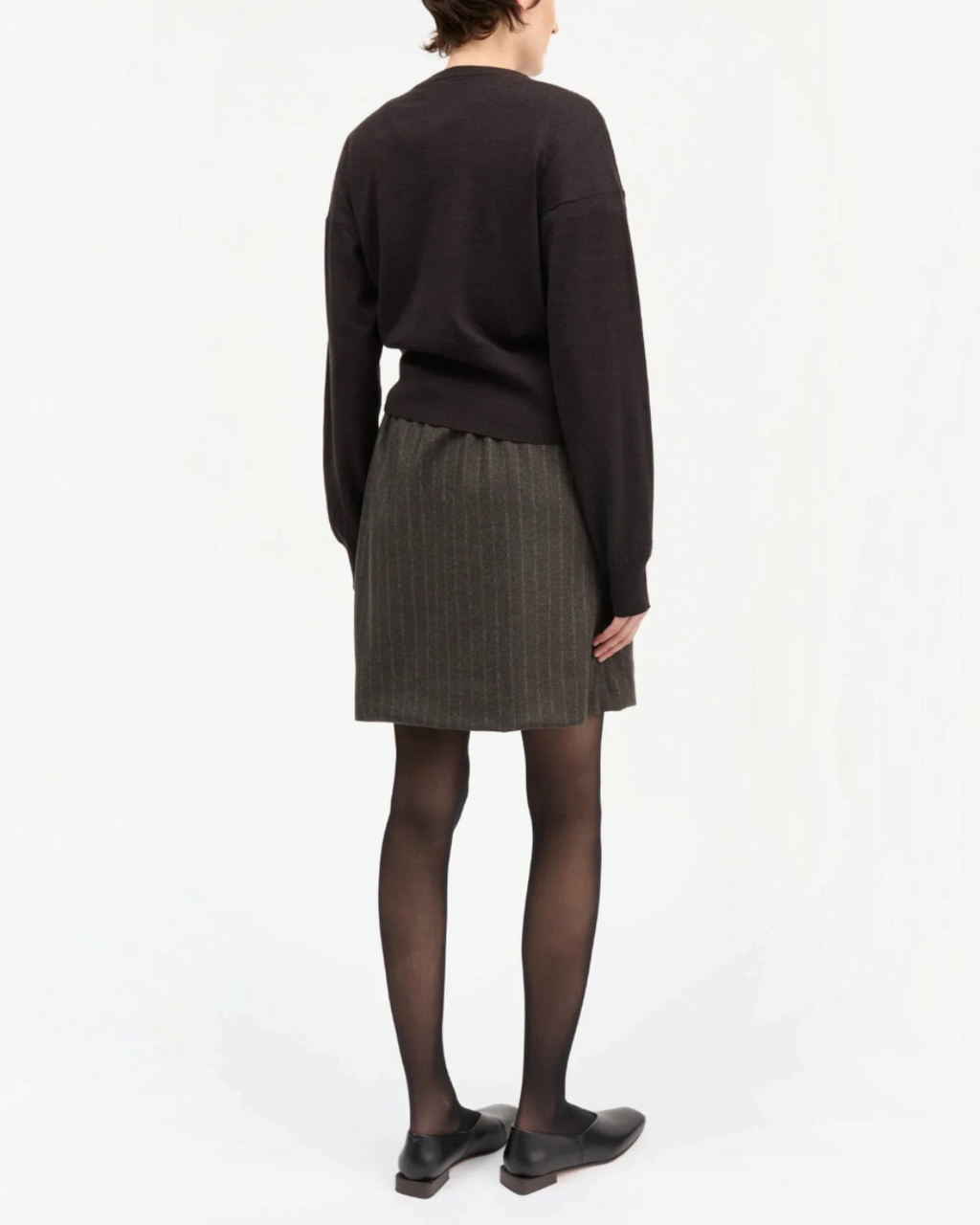 Rear view of a short skirt Skall Studio in brown and black recycled wool with fine stripes worn by a model