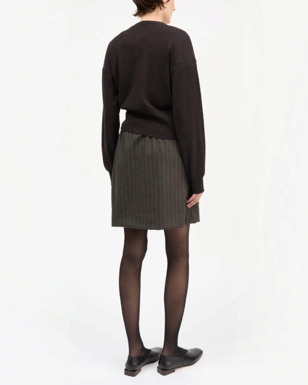Rear view of a short skirt Skall Studio in brown and black recycled wool with fine stripes worn by a model