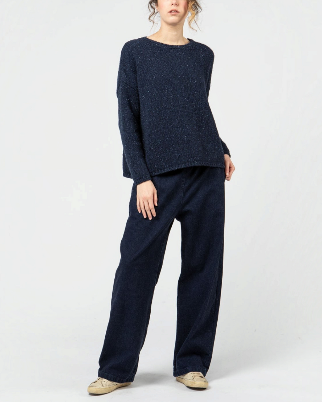 Modèle portant un pantalon denim bleu indigo Merci Paris à coupe ample avec taille élastiquée et pull assorti