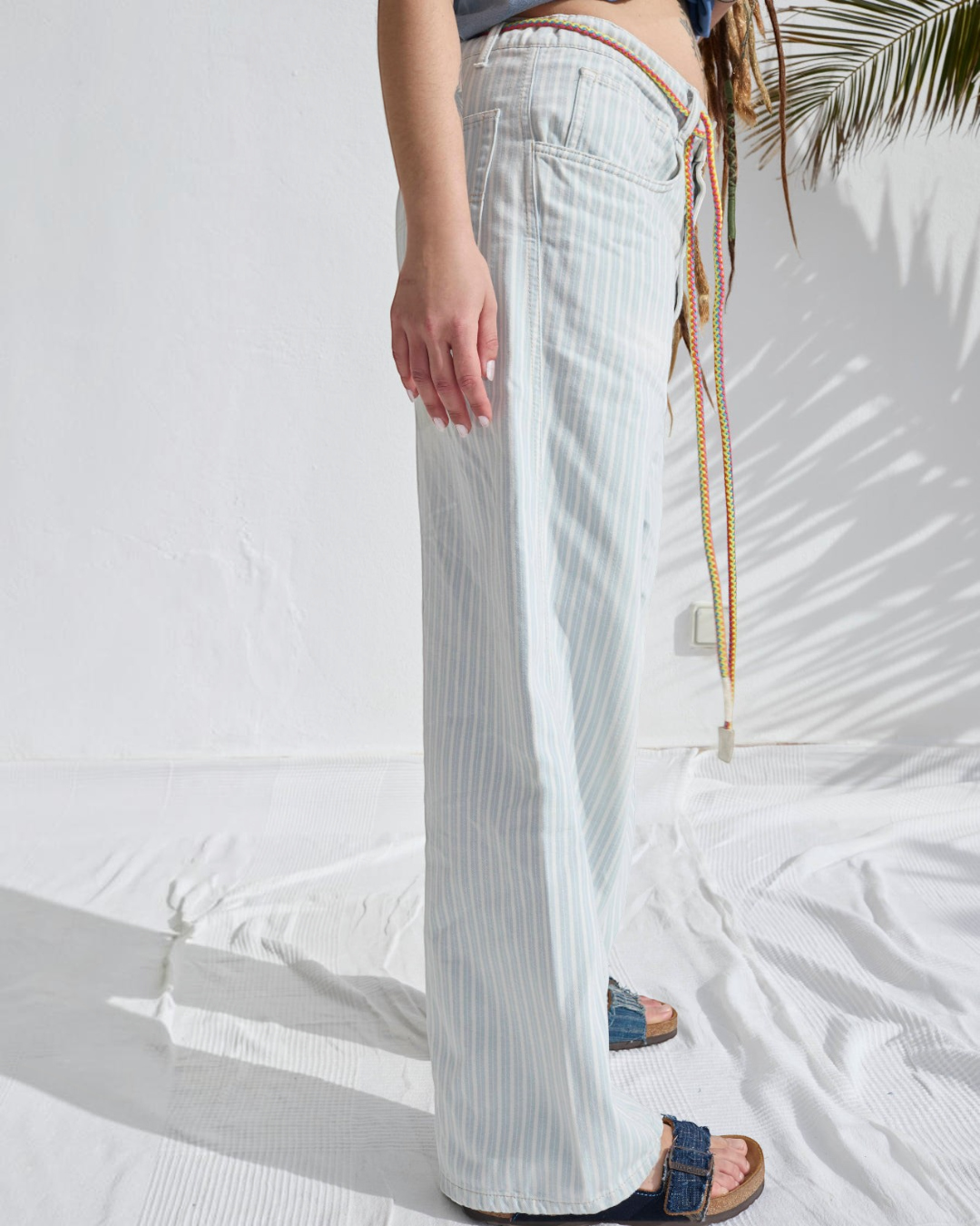 Pantalon P84 Dungaree Merci Paris en coton rayé bleu et écru, coupe ample avec ceinture en corde de chanvre