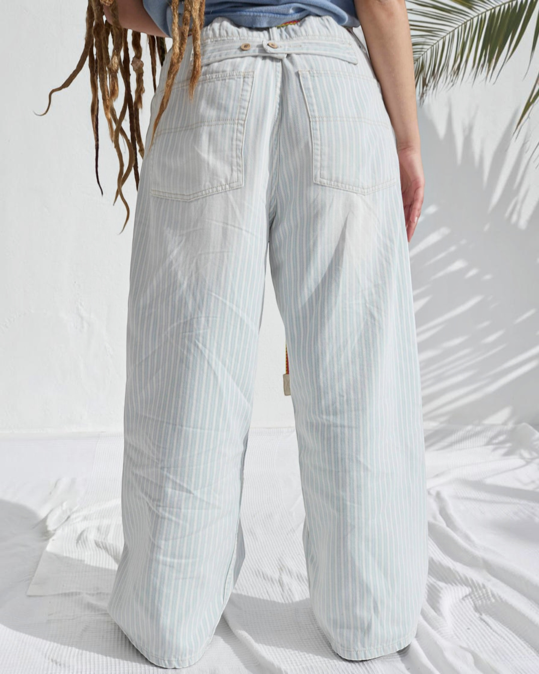 Vue arrière du pantalon P84 Dungaree Merci Paris par Dr. Collectors en coton rayé bleu clair et écru à coupe ample.