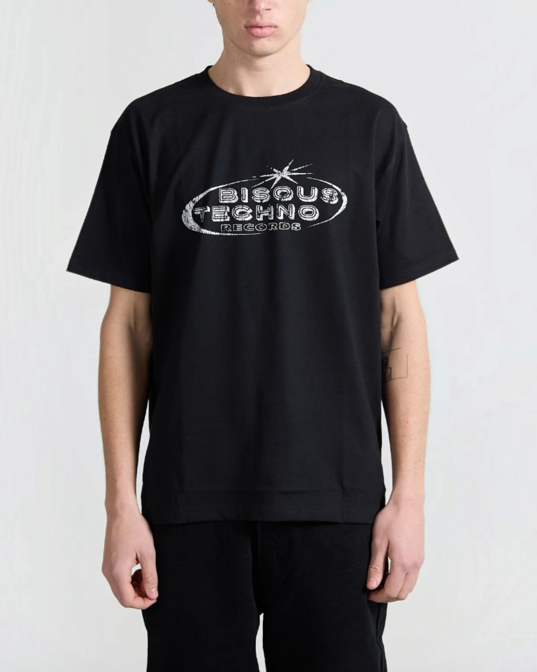 T-shirt noir en coton Merci Paris avec logo Bisous Techno Records blanc sur la poitrine porté par un mannequin