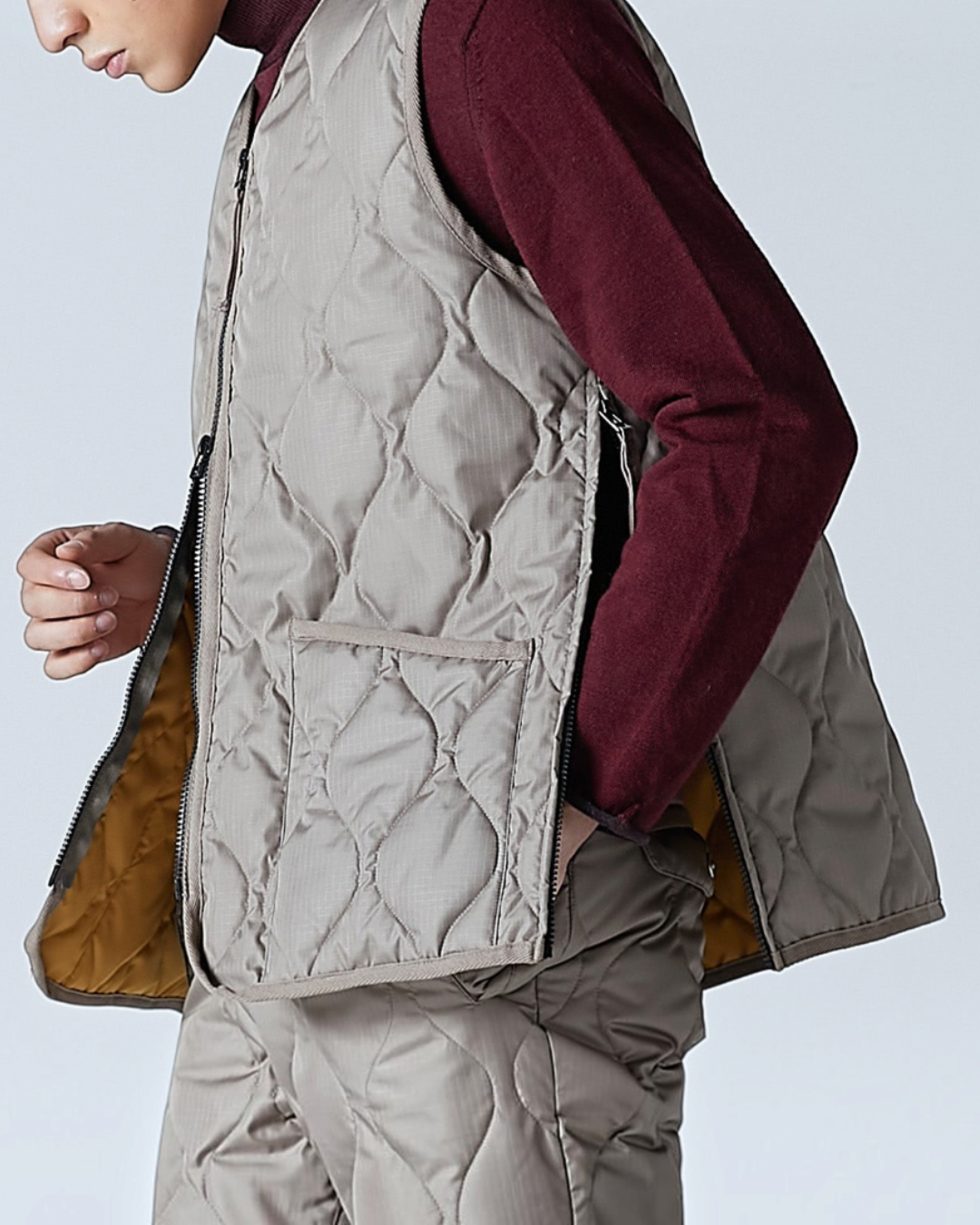 Homme portant un gilet matelassé Merci Paris Taion couleur moka avec col en V, zip double sens et tissu ripstop
