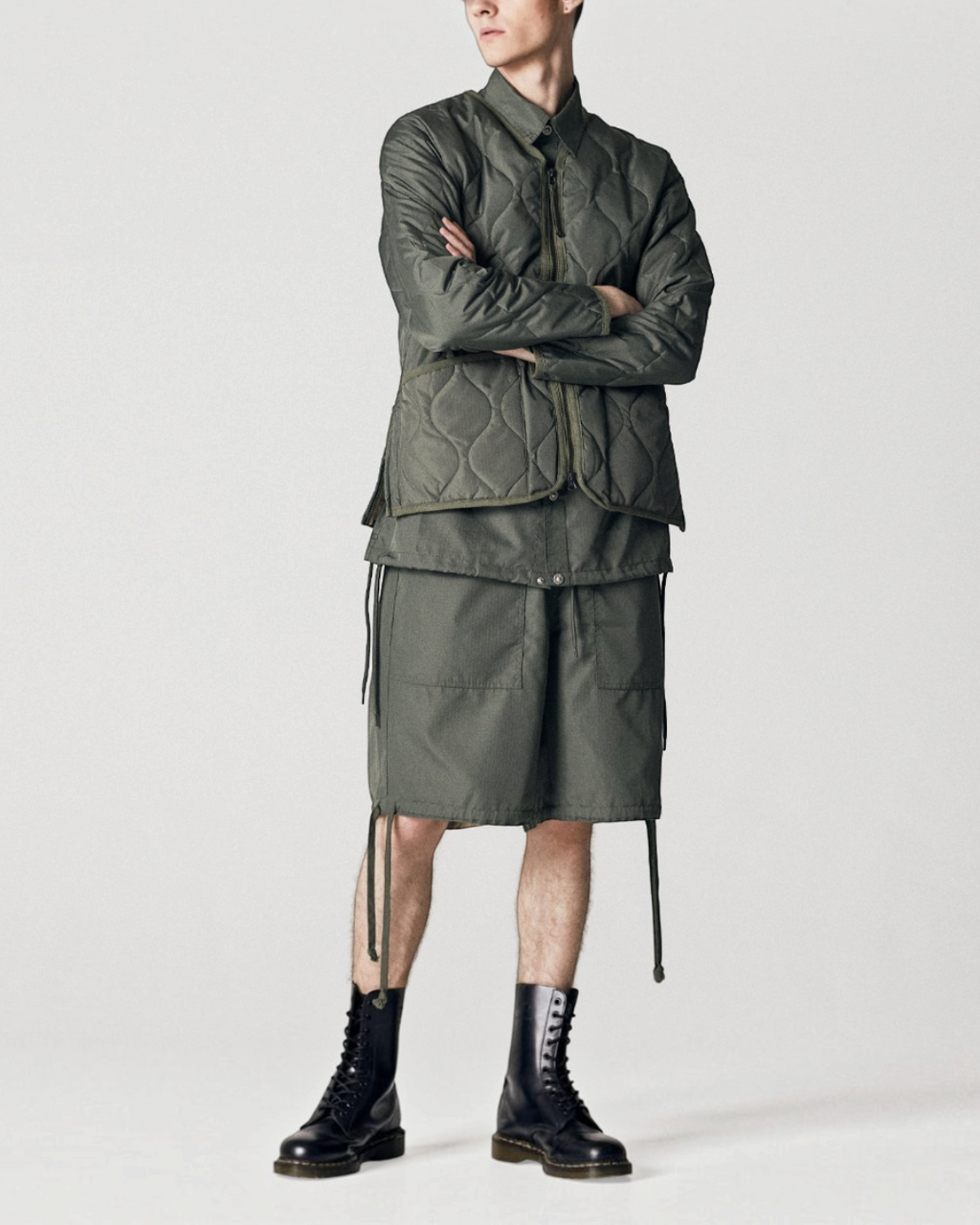 Homme portant une veste matelassée Merci Paris Taion olive à col en V et zip, style militaire avec short assorti