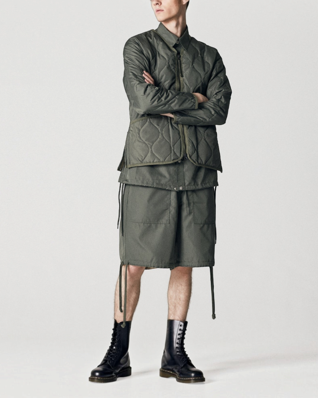 Homme portant une veste matelassée Merci Paris Taion olive à col en V et zip, style militaire avec short assorti