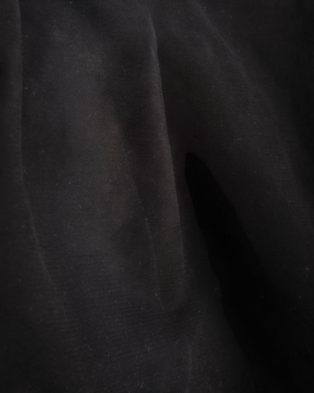 Gros plan sur la texture du tissu en coton noir du pantalon Officer Chino de la marque Merci Paris
