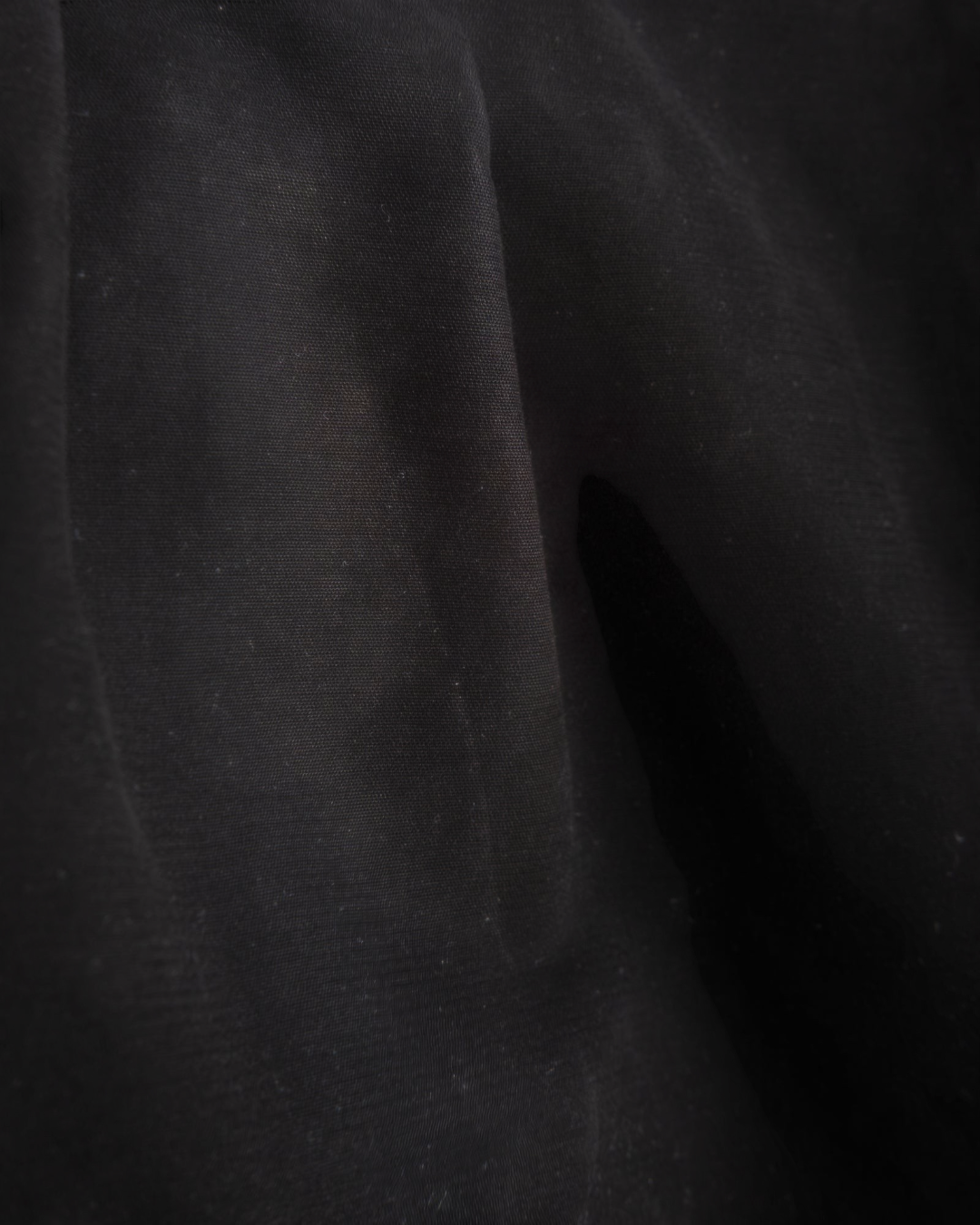 Gros plan sur la texture du tissu en coton noir du pantalon Officer Chino de la marque Merci Paris