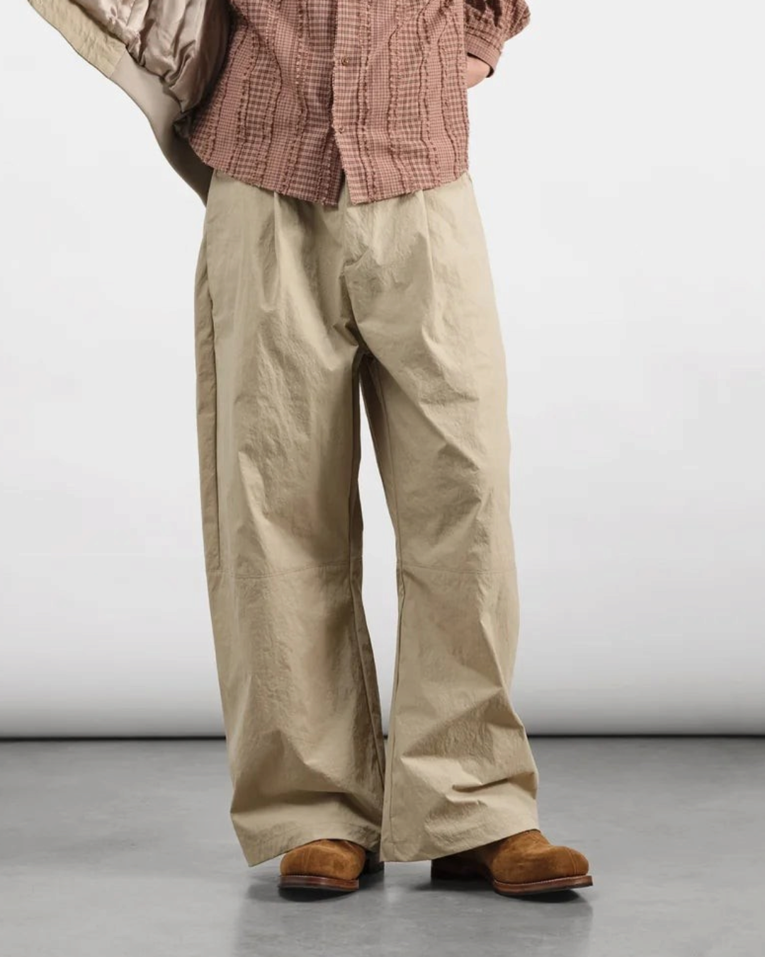Pantalon ample beige Merci Paris en toile de nylon légère avec plis sur le devant porté par un homme