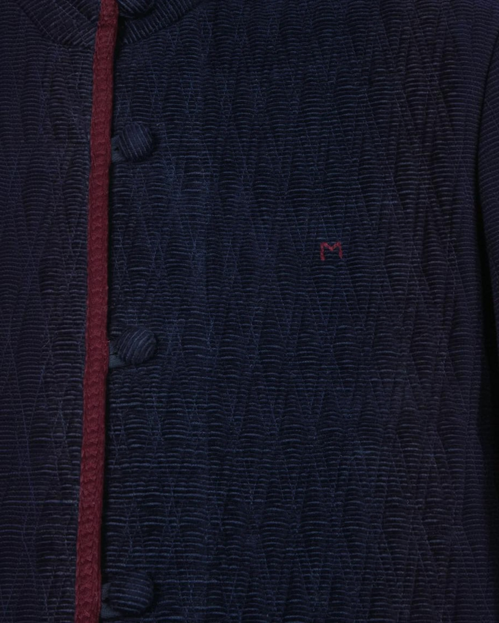 Gros plan sur la veste Marianne Merci Paris en velours de coton bleu marine avec passepoil contrastant bordeaux