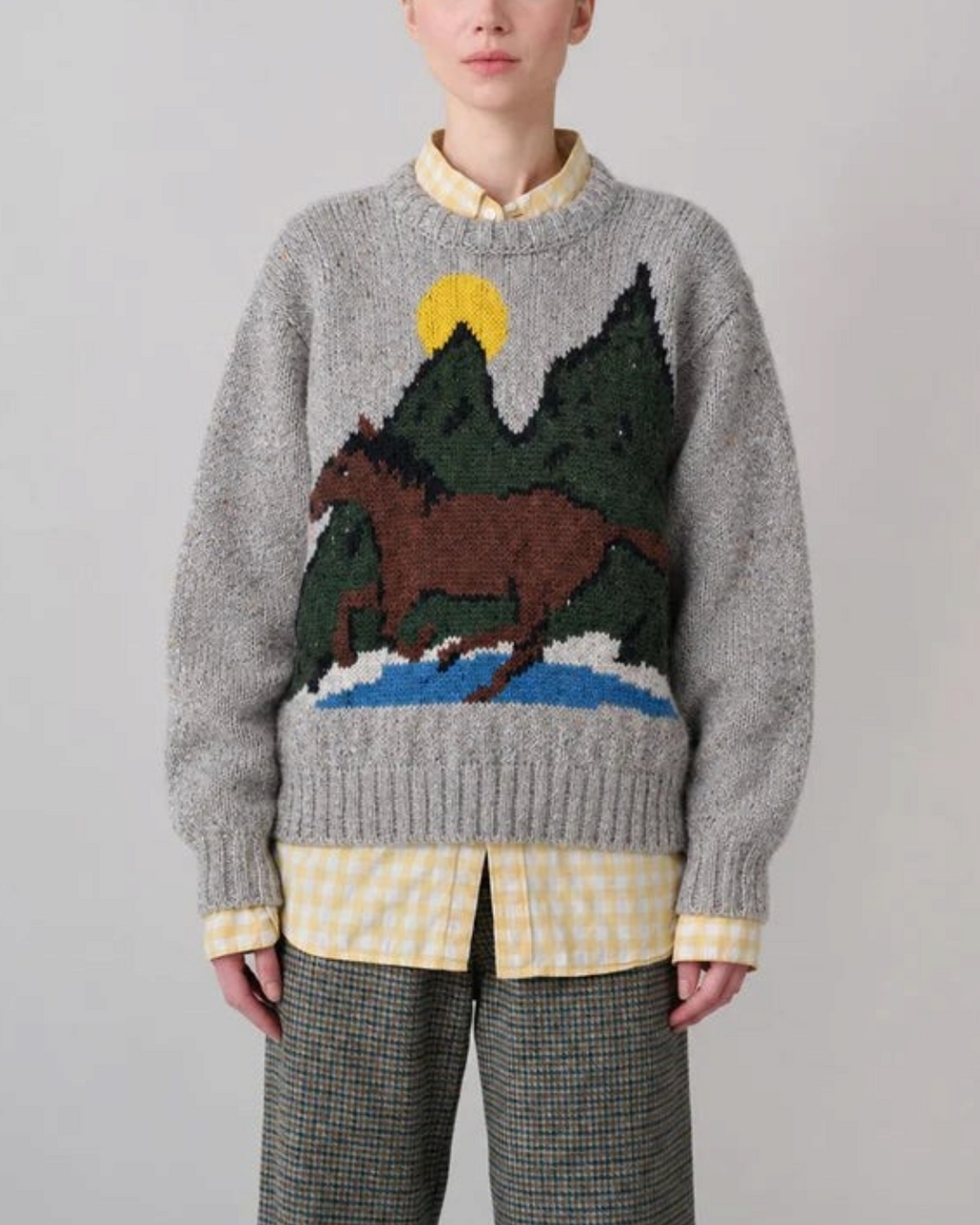 Pull gris en laine et mohair Merci Paris avec motif cheval et paysage, tricoté en Irlande, porté par une femme