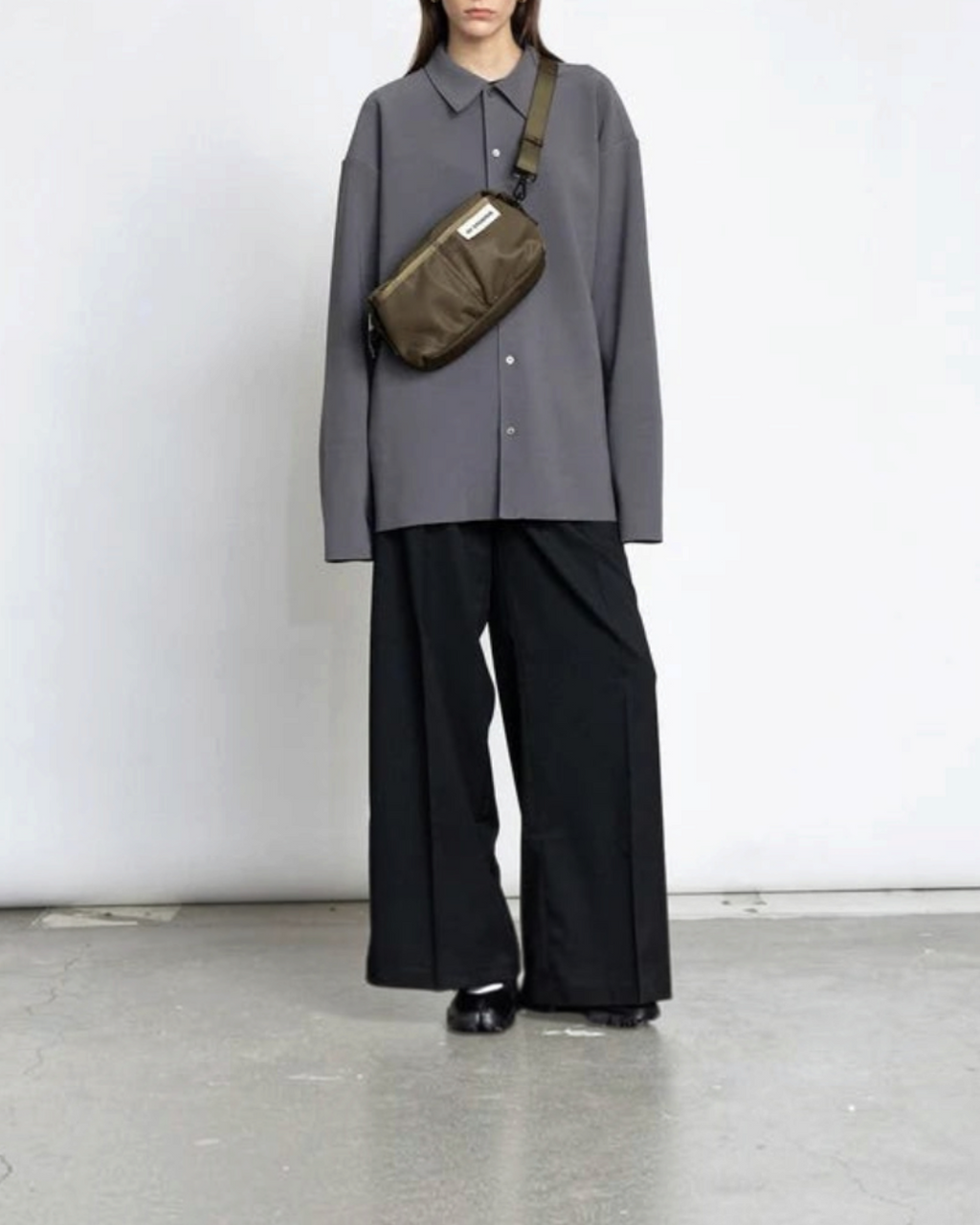 Modèle portant un sac bandoulière kaki Merci Paris en nylon recyclé au design minimaliste scandinave