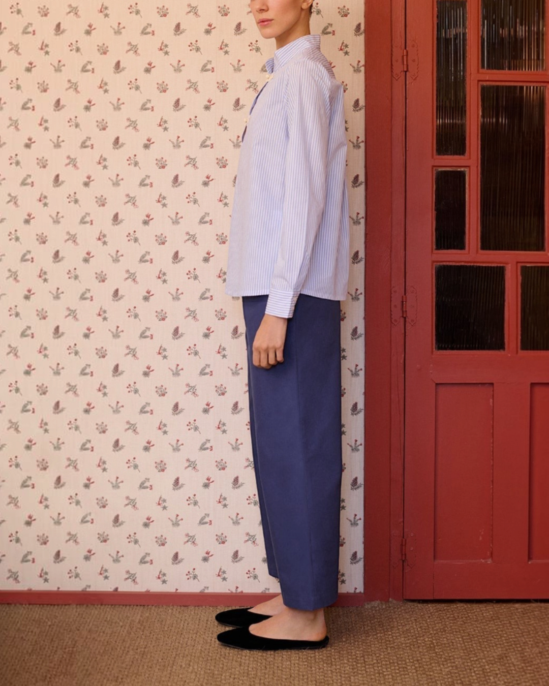 Mannequin portant la chemise rayée bleue Maria De La Orden chez Merci Paris, vue de profil dans un intérieur.