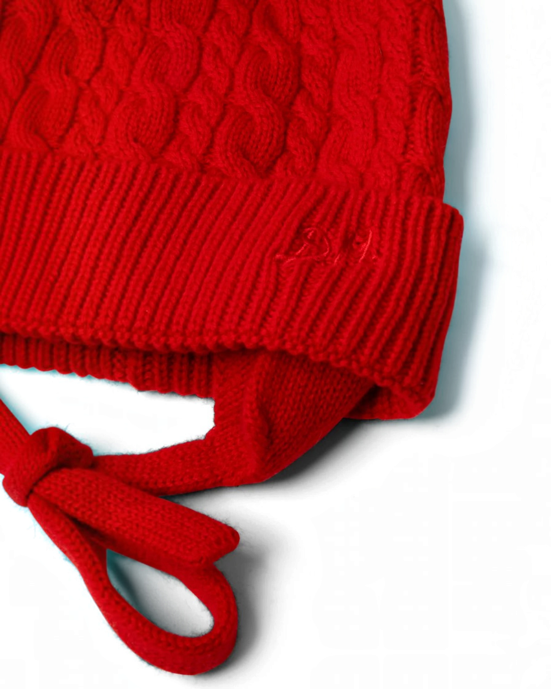 Bonnet rouge en laine et cachemire Merci Paris avec maille torsadée, cache-oreilles et liens à nouer
