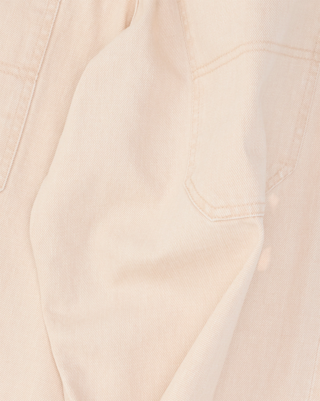 Gros plan sur le jean en denim japonais beige pêche de Merci Paris avec ses poches arrière profondes et coutures